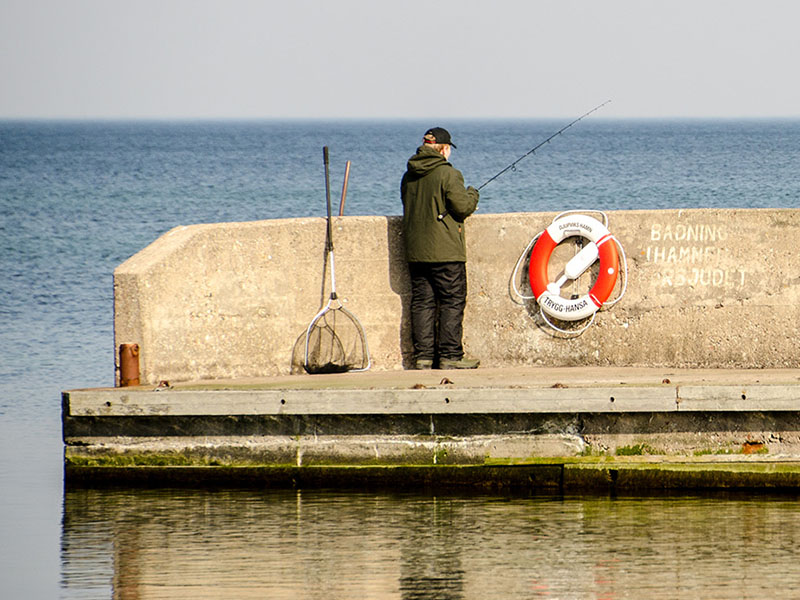 Man fiskar från pir i Djupviks Hamn, Gotland