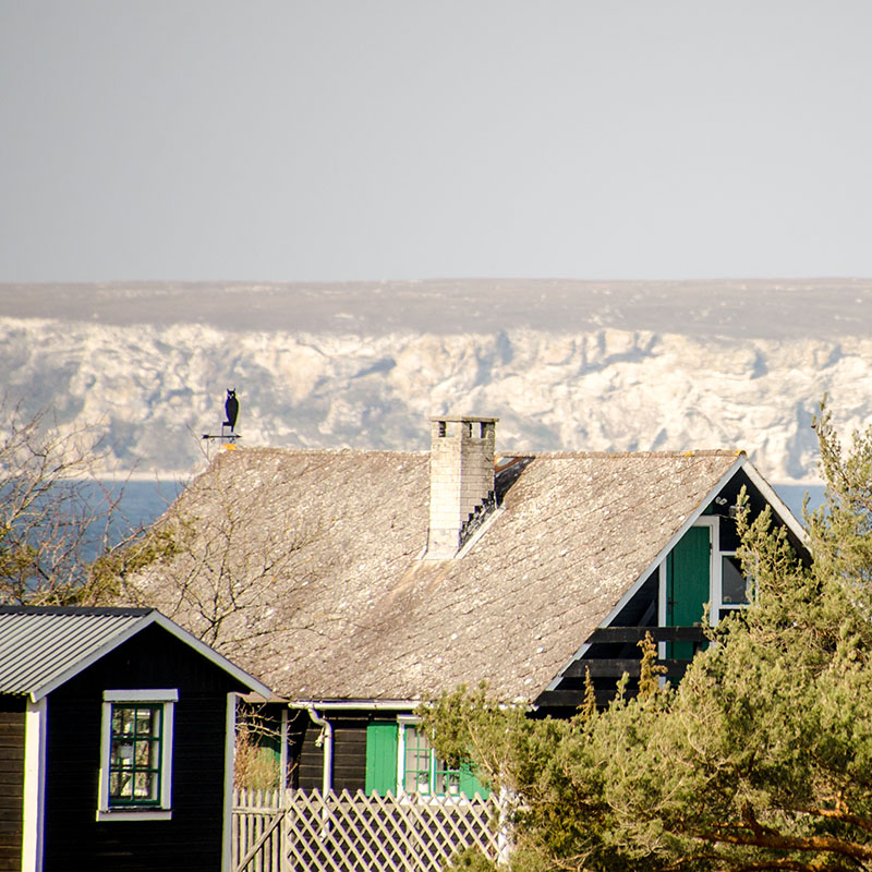 Utsikt över hustak, hav och berg i Djupviks Hamn, Gotland