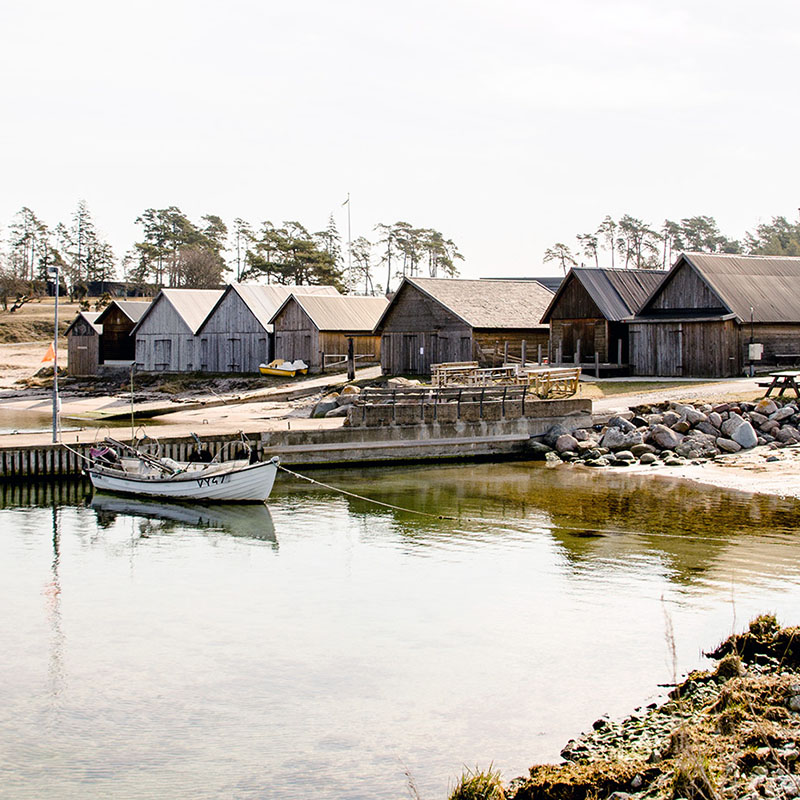 Stugor, strand och båt liggandes i vackra Djupviks Hamn på Gotland